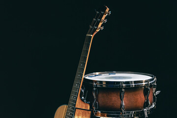 Acoustic guitar and snare drum on a black background isolated.