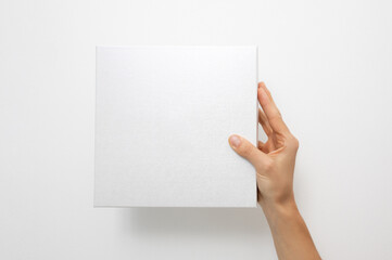 Mockup of white box on white background. Hand holding blank cardboard gift