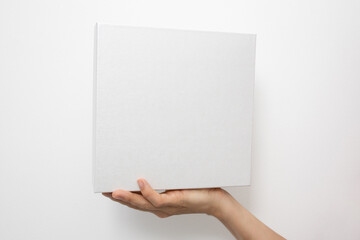 Mockup of white box on white background. Hand holding blank cardboard gift