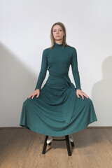 Fototapeta premium Serie of studio photos of young female model wearing maxi green cotton dress with long sleeves