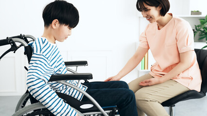 車椅子に乗った男の子を診察する看護師　医師