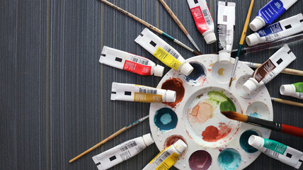 top view of the colored palette with colorful watercolor paint tubs and brushes isolated on the table