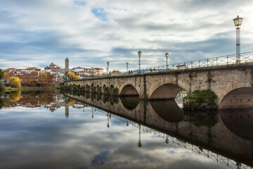 View of the city of Mirandela, Portugal, with the medieval bridge and the Tua river in the foreground, on a misty autumn morning.