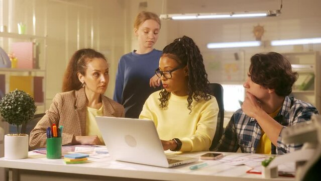 African American woman leader of the group tells his employees about the new project and makes a presentation on a laptop. Young creative team of managers or startups work together in the office. - Powered by Adobe