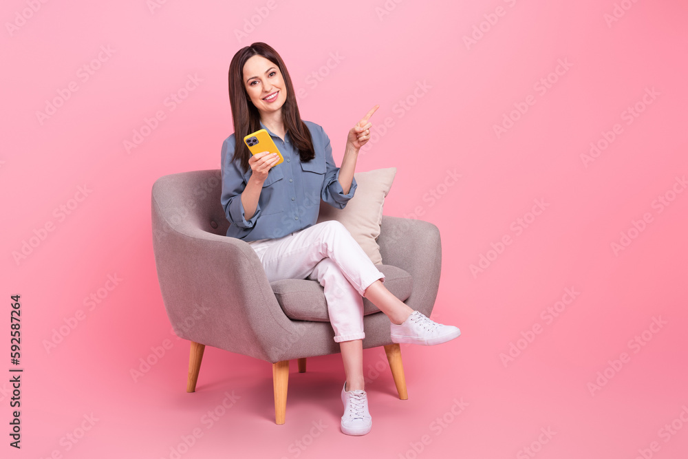 Sticker Full body photo of confident manager young lady sit chair direct finger mockup hold phone cheap phone accessories isolated on pink color background