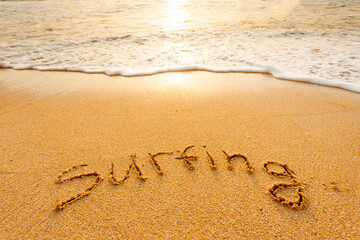 The word surfing written in the sand on the beach