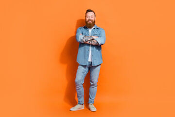 Full body photo of young hipster crossed arms wear jeans shirt red hair beard professional barber hairdresser isolated on orange color background