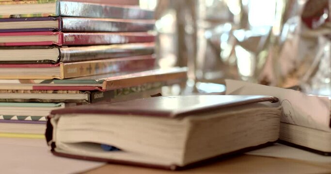 The place of accumulation of printed materials in the classroom. Children's books stack even. The teacher's notes are on the table. Notebook bokeh effect, pen in pages. 2.3.2023. CZ, Kladno, Polska.