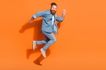 Fototapeta na wymiar Full length profile portrait of carefree overjoyed person jump rush empty space isolated on orange color background
