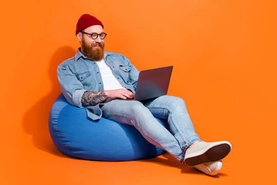 Full body photo of geek nerd guy working on laptop online shopping sit bag chair isolated bright color background