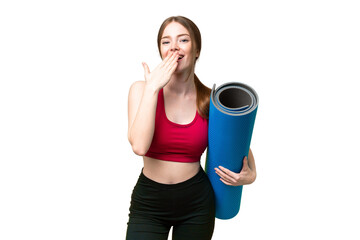 Young sport woman going to yoga classes while holding a mat over isolated chroma key background happy and smiling covering mouth with hand