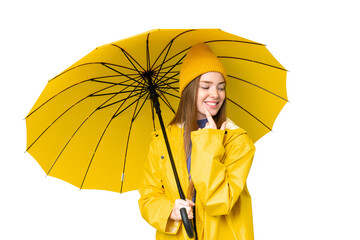 Young pretty woman with rainproof coat and umbrella over isolated chroma key background looking to the side and smiling