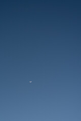half moon shining bright at the large blue sky