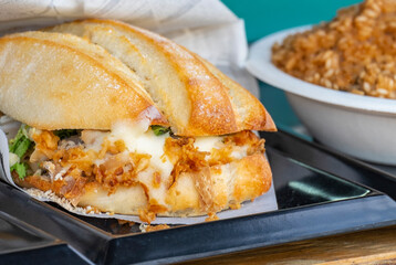 The perfect sandwich with cheese, bacon, pickles, tomatoes, onions and turnips for sale at the counter of a van at a food truck