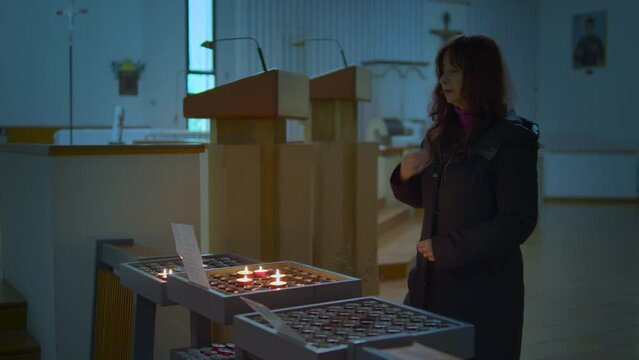 una donna accende una candela in chiesa e prega