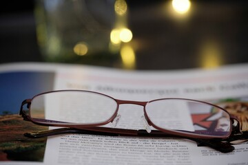 Closeup of reading glasses on an open book on a a table.