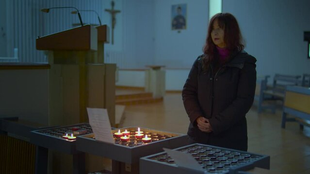 una donna accende una candela in chiesa e prega