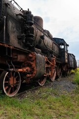 Fototapeta na wymiar Vertical shot of steamed locomotive in a junkyard