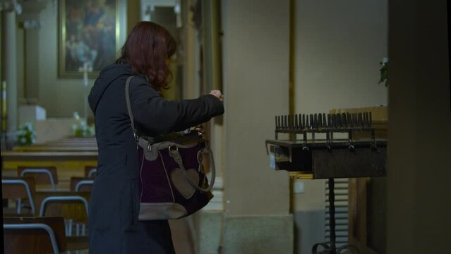 donna prega in chiesa e accende una candela presso un altare