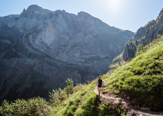 Hiker walking on a mountain trail with a view over a gorge to cliffs beyond