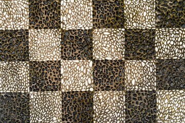 Checkered pattern mosaic floor made of black and white pebbles on the island in Greece.