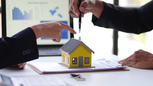 Businessman and real estate agent discussing the terms of the home purchase agreement contract document, mortgage, lease, rent and legal signing.