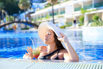 Young woman enjoying cocktail at the swimming pool
