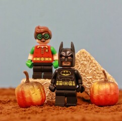 Obraz premium View of Batman and Robin lego figurine standing by the hays and pumpkins - Halloween concept