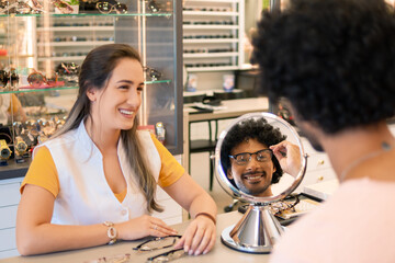 Consumer trying glasses with salesperson in optics.
