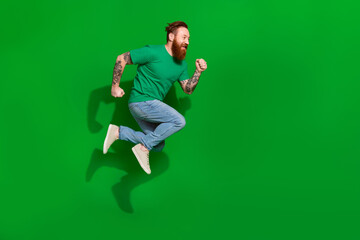 Full size profile portrait of carefree sporty person jump running empty space isolated on green color background © deagreez