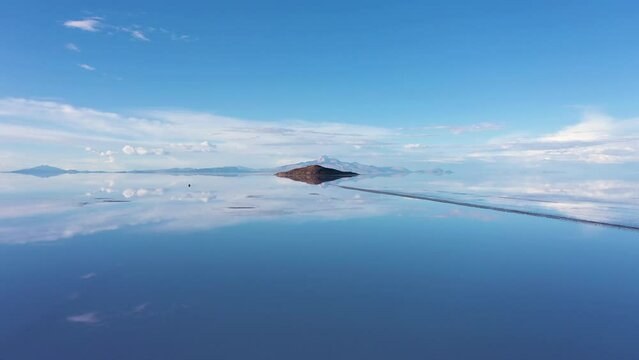 Uyuni Salt Flats. Aerial View. Altiplano, Bolivia. Rainy Season. Tunupa Volcano and Incahuasi Island. Clouds Reflection on Water in Lake Surface. Drone Flies Forward and Upwards