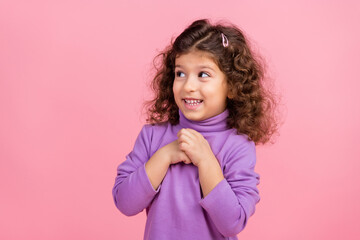 Photo of tricky excited small kid wear violet sweater looking empty space arms chest isolated pink color background