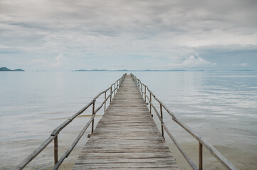Fototapeta na wymiar Picturesque scenery of empty wooden pier placed on rippling sea under cloudy sky