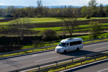 White modern delivery small shipment cargo courier van moving fast on motorway road to city urban suburb.	
