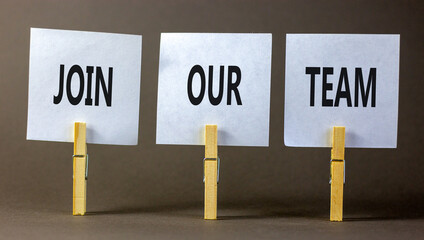 Join our team symbol. Concept words Join our team on white paper on wooden clothespin on a beautiful grey table grey background. Business and join our team concept. Copy space.