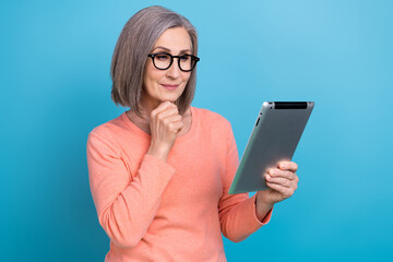 Photo of smart intelligent woman wear coral shirt spectacles arm chin typing modern gadget isolated blue color background