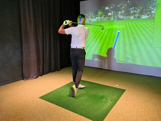 Professional male golfer holding club playing golf indoors on golf simulator