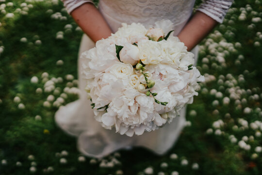 The bride holds flower bouquets in her hands, photographed in close-up