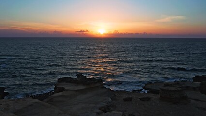 Aerial view over beautiful  ocean during  sunset. Top view to the ocean in summer day while sunset - closeup. Drone view of a Scenic slow motion ocean waves. Beautiful sunrise over ocean