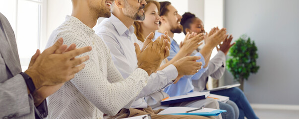 Joyful and smiling people who are satisfied with great business presentation are applauding after...