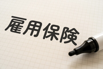 雇用保険と書かれたノートとマーカー