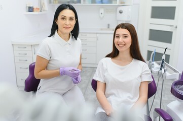 people, medicine, stomatology and health care concept - happy female dentist with patient girl talking at dental clinic office