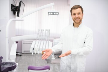 Attractive male dentist in doctors white lab coat posing in modern dental office
