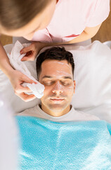 Beautician doing face treatment in beauty salon to a man..