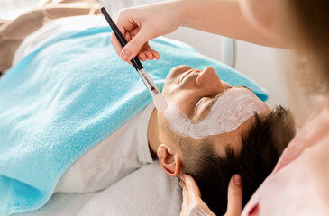 Beautician doing face treatment in beauty salon to a man..