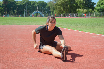 young sporty woman on the floor stretching leg and hip, touching toe with hand