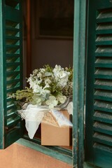 Vertical closeup of a white bouquet of flowers on a green windowsill