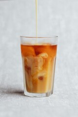 Vertical of pouring vanilla soy milk into speciality coffee cold brew drink with ice