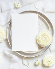 Wedding table setting with card near cream roses and white silk ribbons top view, mockup