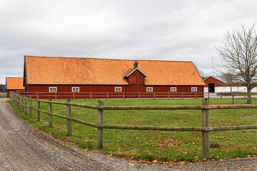 Fototapeta premium Old red wooden house in vintage Scandinavian style. Traditional ancient Sweden building in the village. A big farm.
